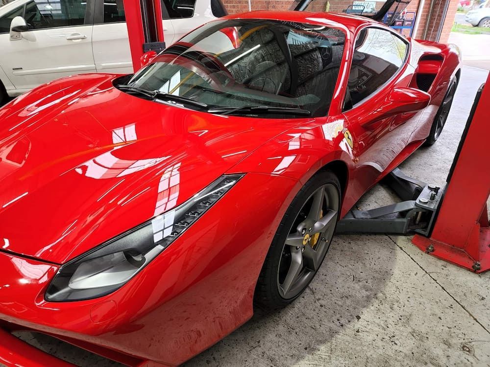 A Red Sports Car Is Sitting On A Lift In A Garage — COOTA Automotive Services In Ballarat East, VIC