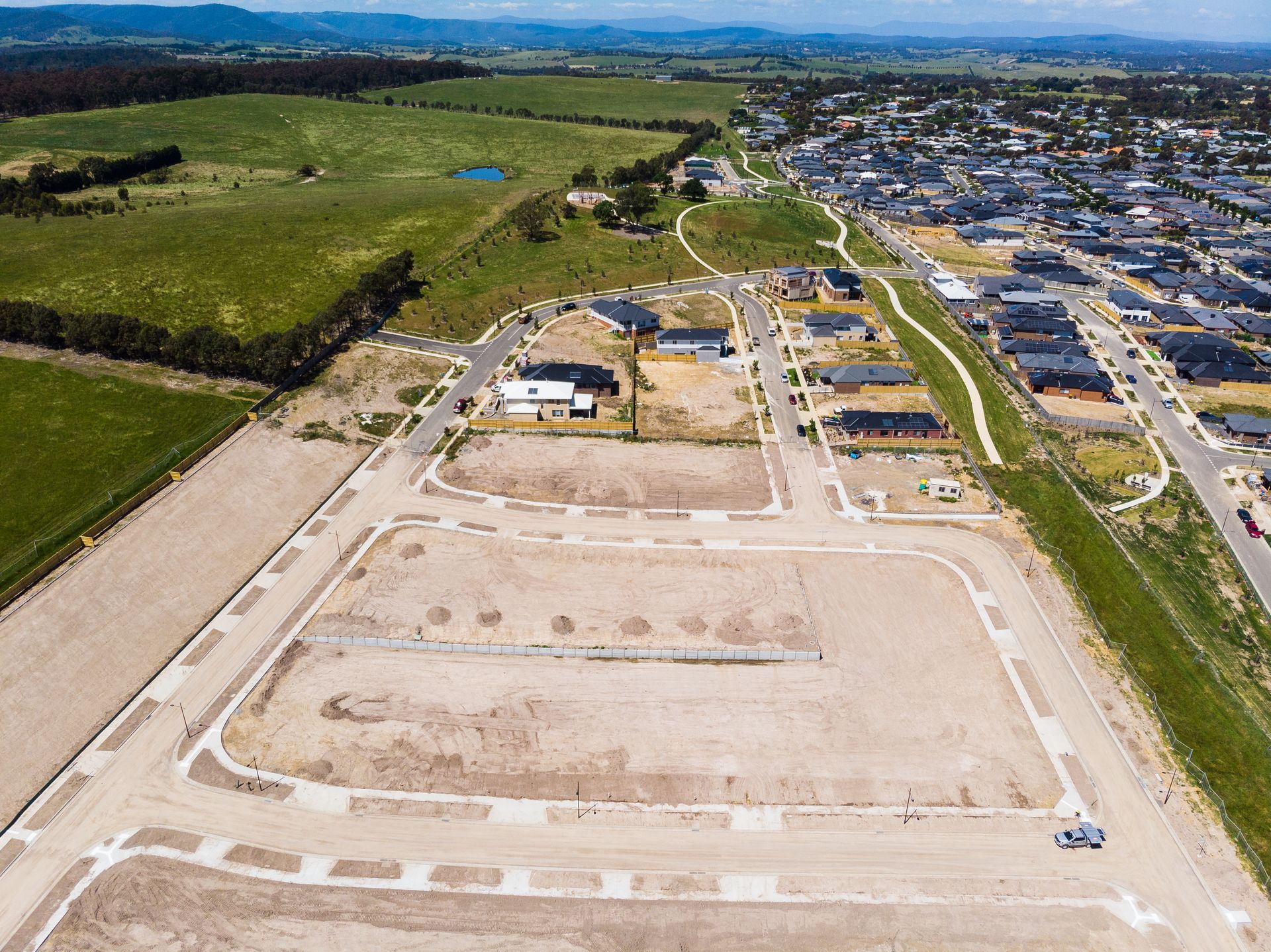 Aerial view of a new housing development beside green farmland and open fields