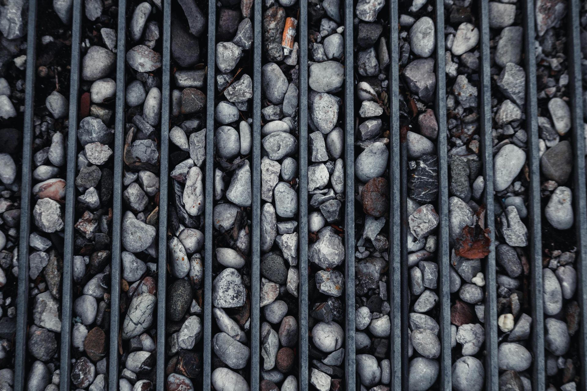 Rows of gray pebbles separated by vertical metal bars, viewed from above