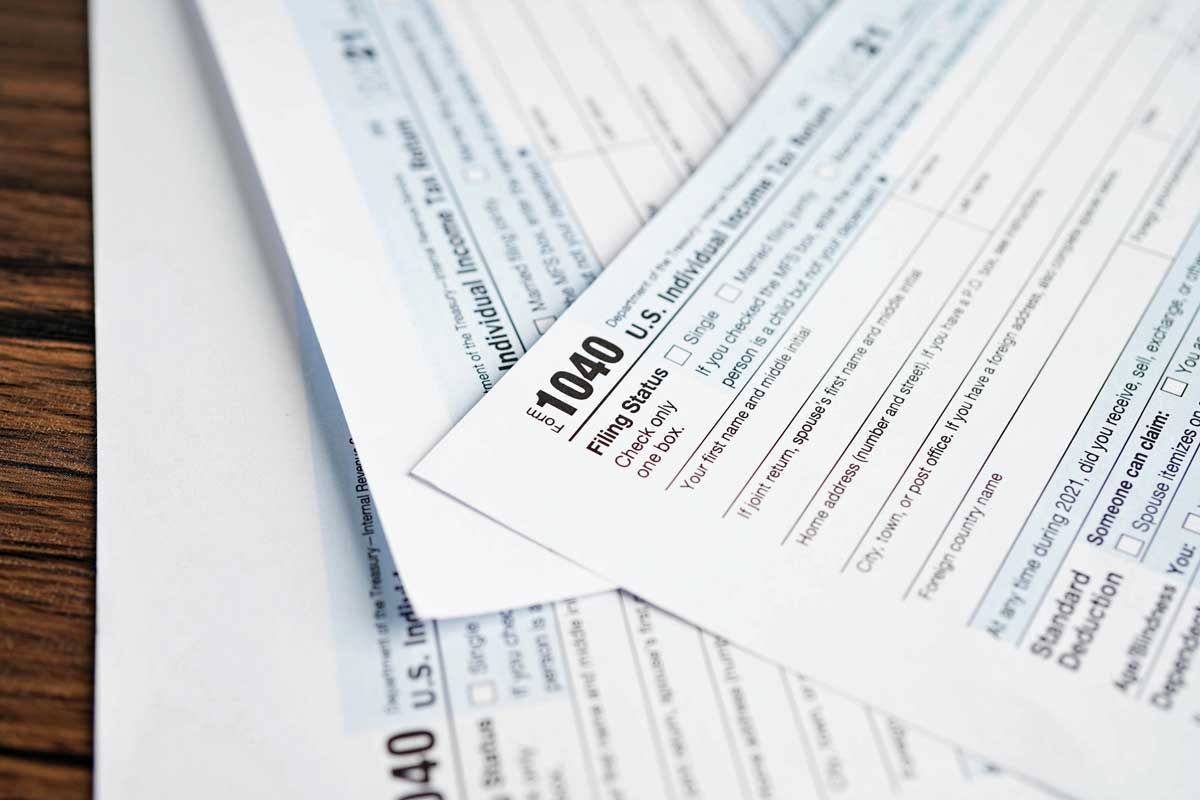 Two U.S. tax forms (1040) on a wooden surface, partially visible, with text and fields.