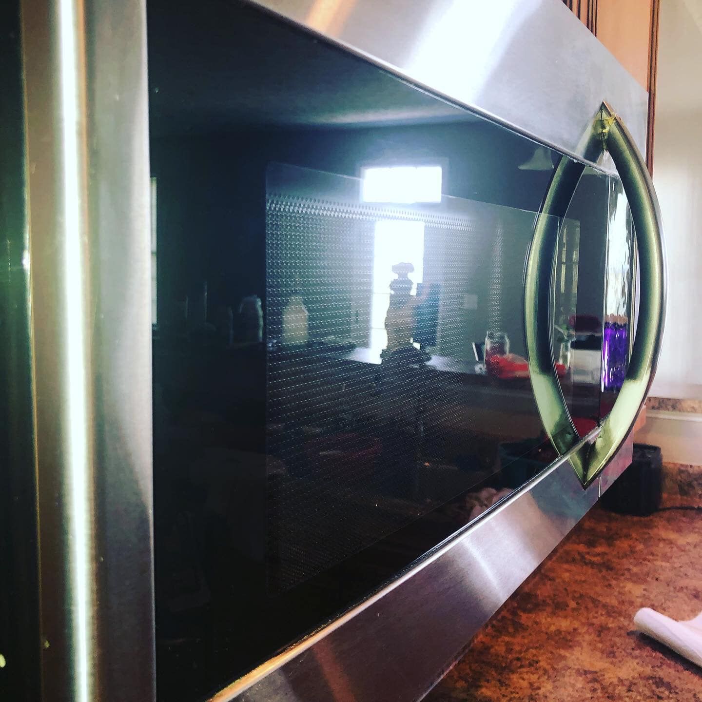 A close-up, angled view of a stainless steel and black microwave oven with a curved handle.