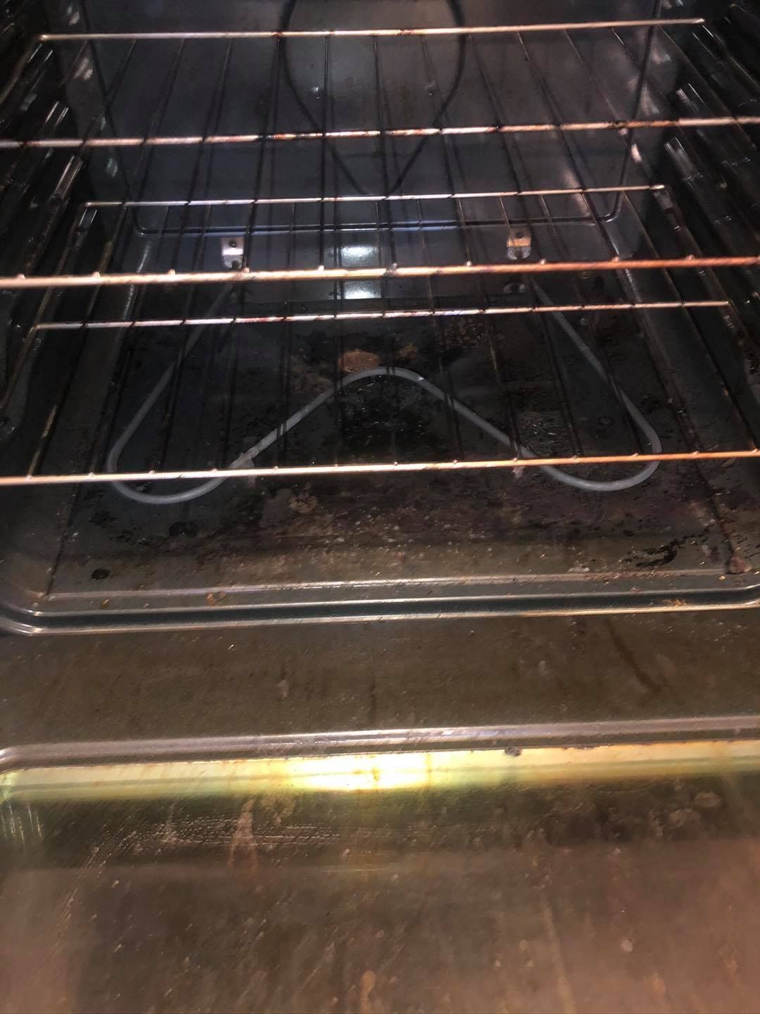 A slightly dirty residential oven interior with a metal wire rack installed above the heating element.