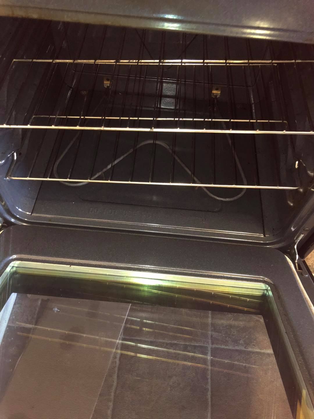 The inside of an empty oven with two wire racks installed, viewed through the open glass door.