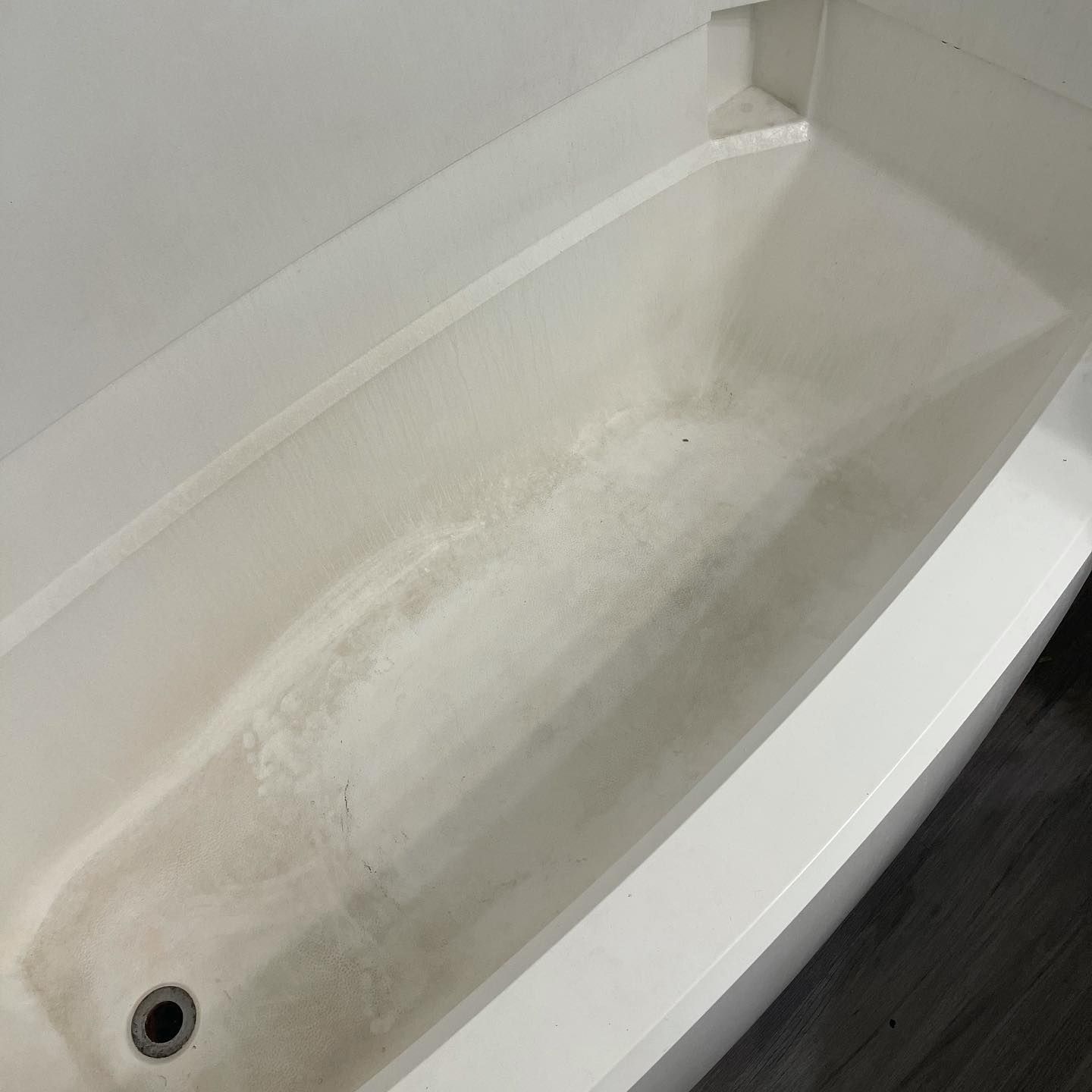 A white bathtub with significant dark, dingy stains covering the bottom basin.