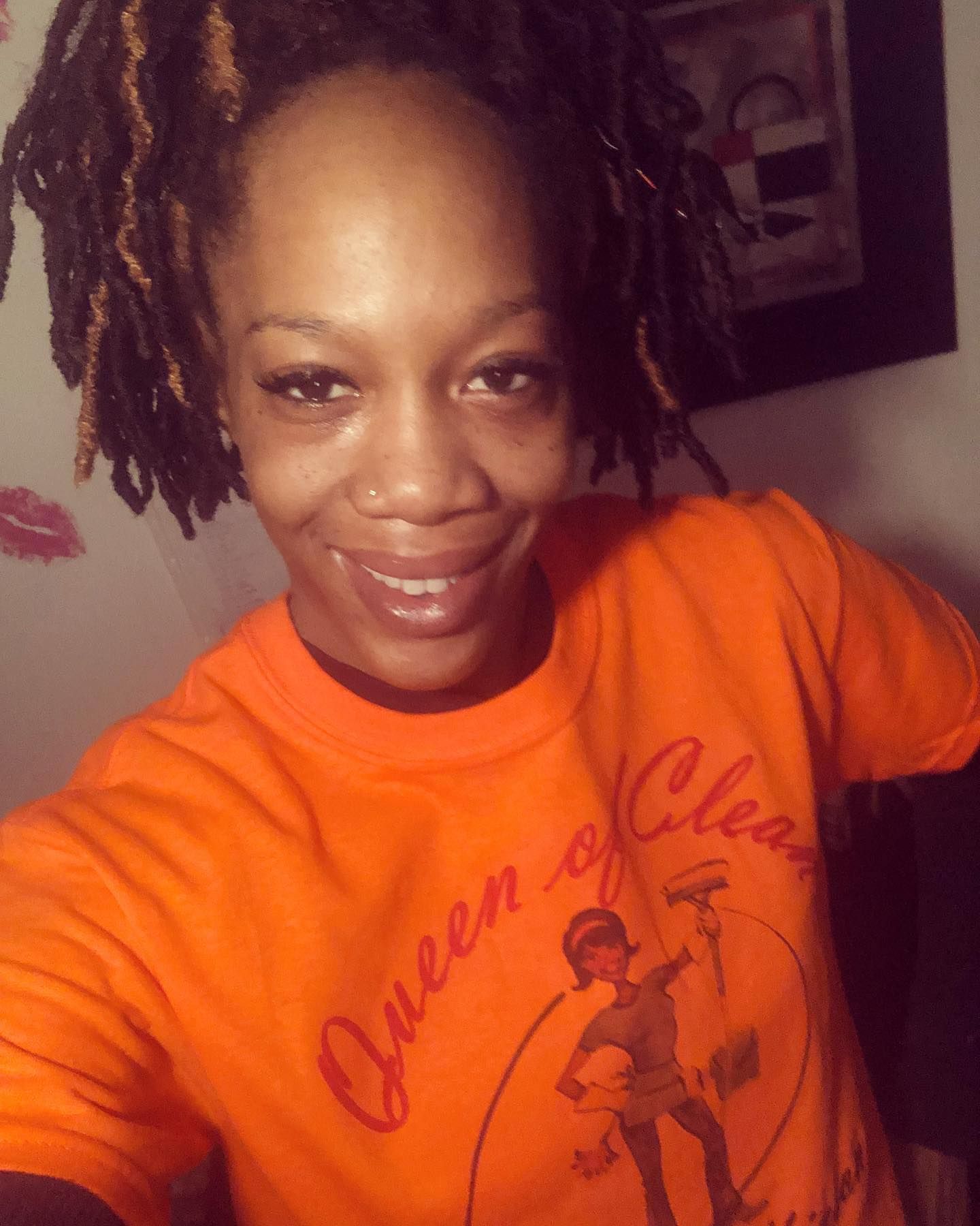 A person smiling at the camera, wearing an orange 