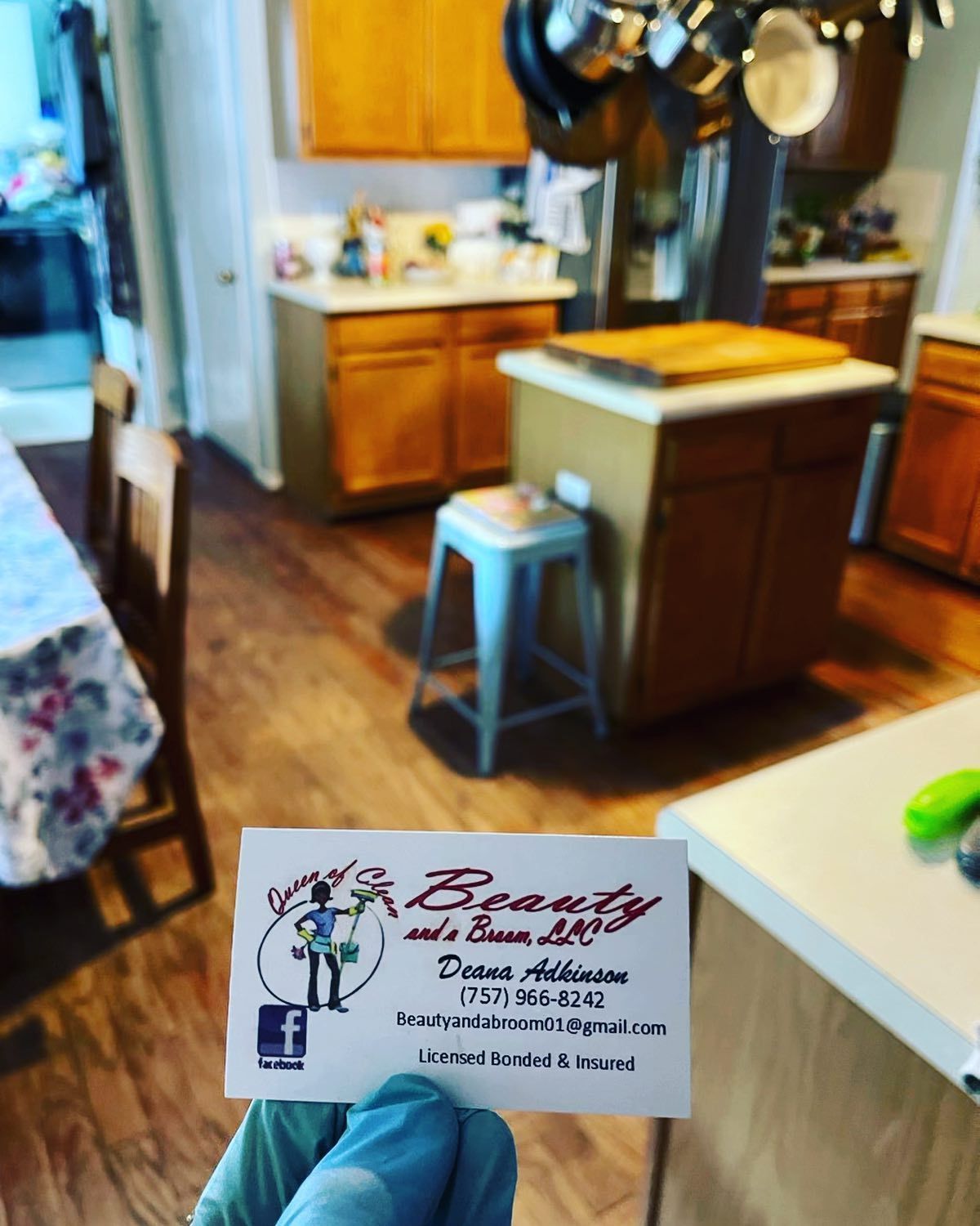 A hand in a blue glove holds a business card for 