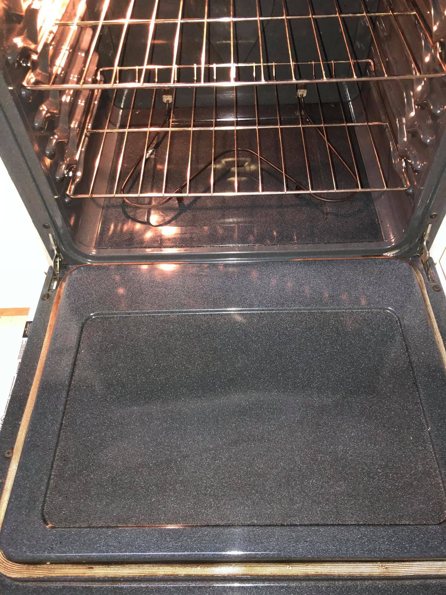 An open oven interior with two wire racks and a dark, speckled-finish door.