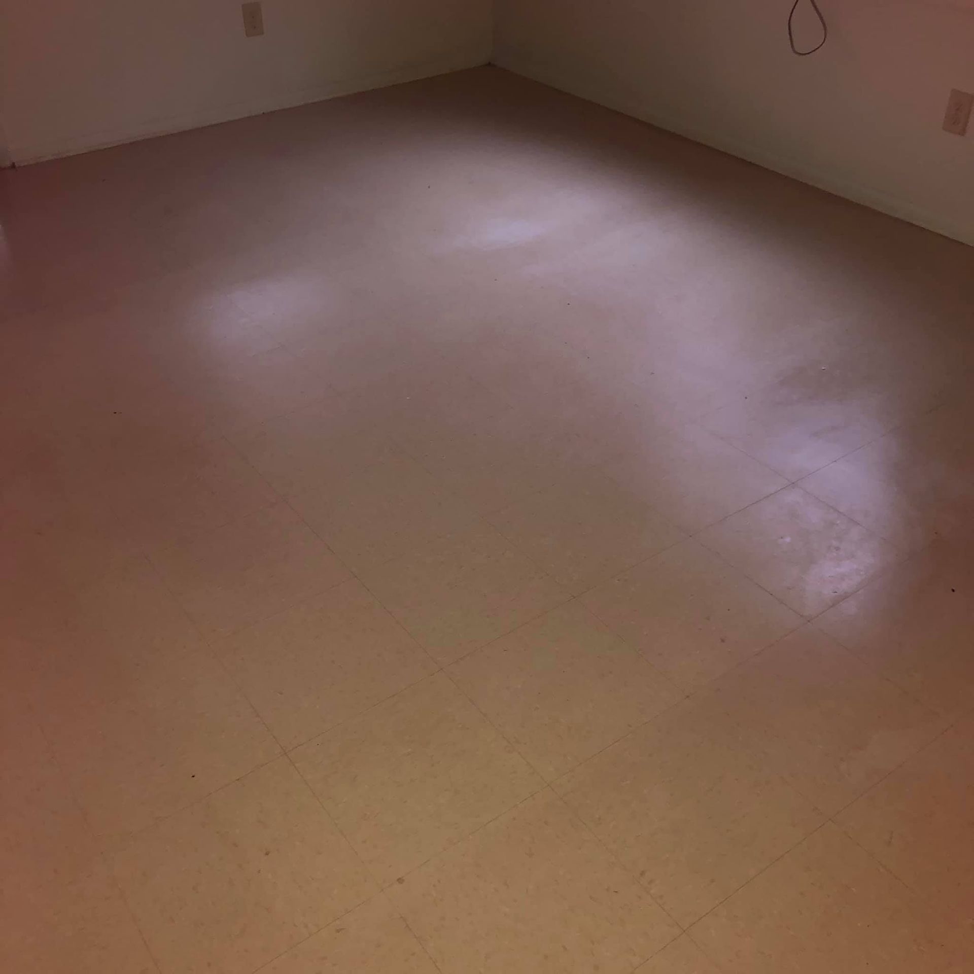 Empty room with light-colored, square tile flooring and plain walls with two visible electrical outlets.