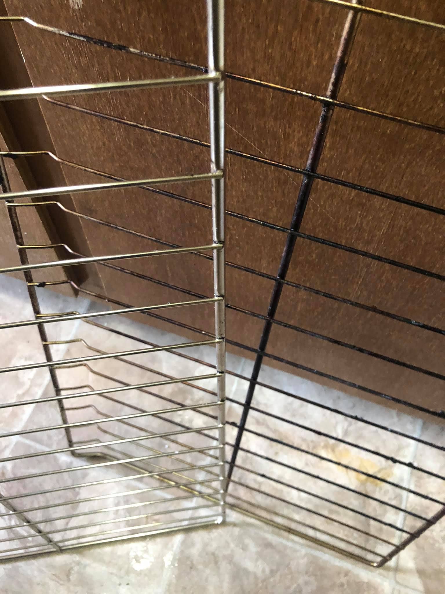 Two wire oven racks resting on a light-colored surface with a brown wood background.