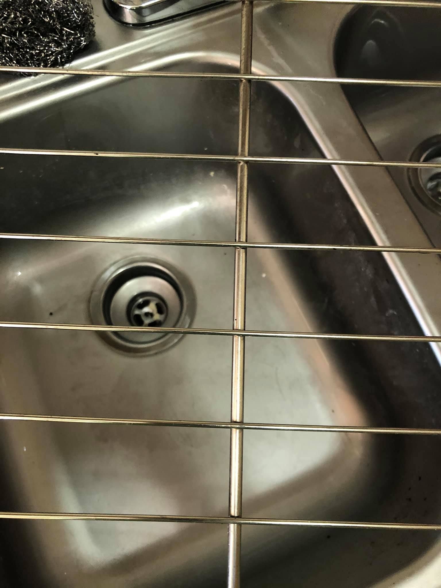 A wire drying rack sits over a dual-basin stainless steel kitchen sink.