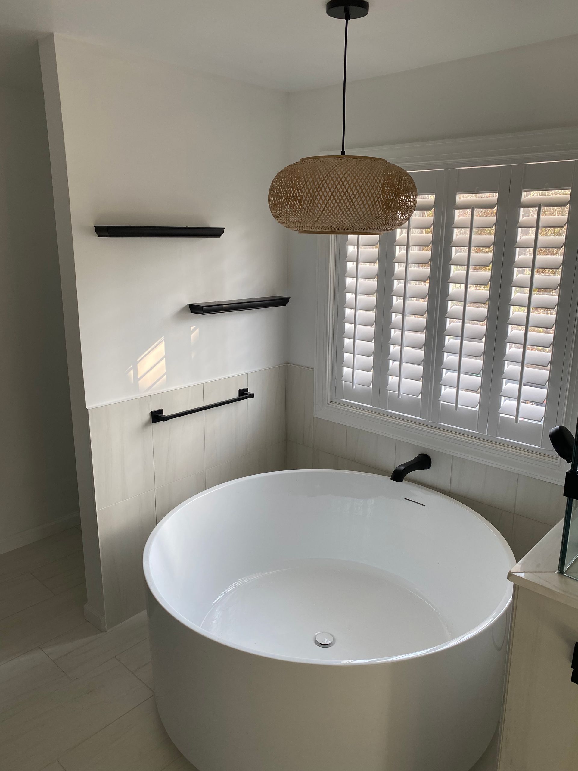 A bathroom with a round bathtub and a window with shutters.