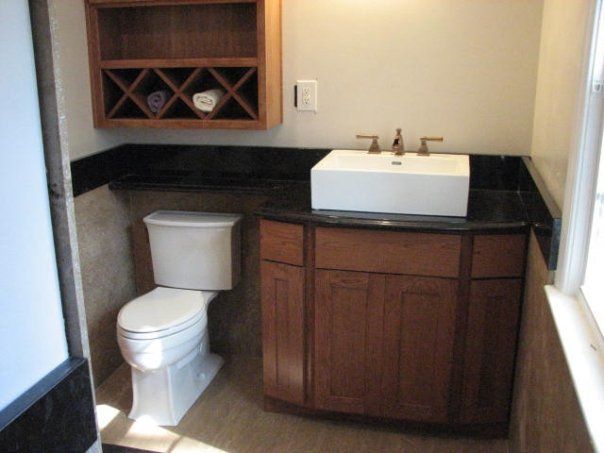 A bathroom with a toilet a sink and a wine rack