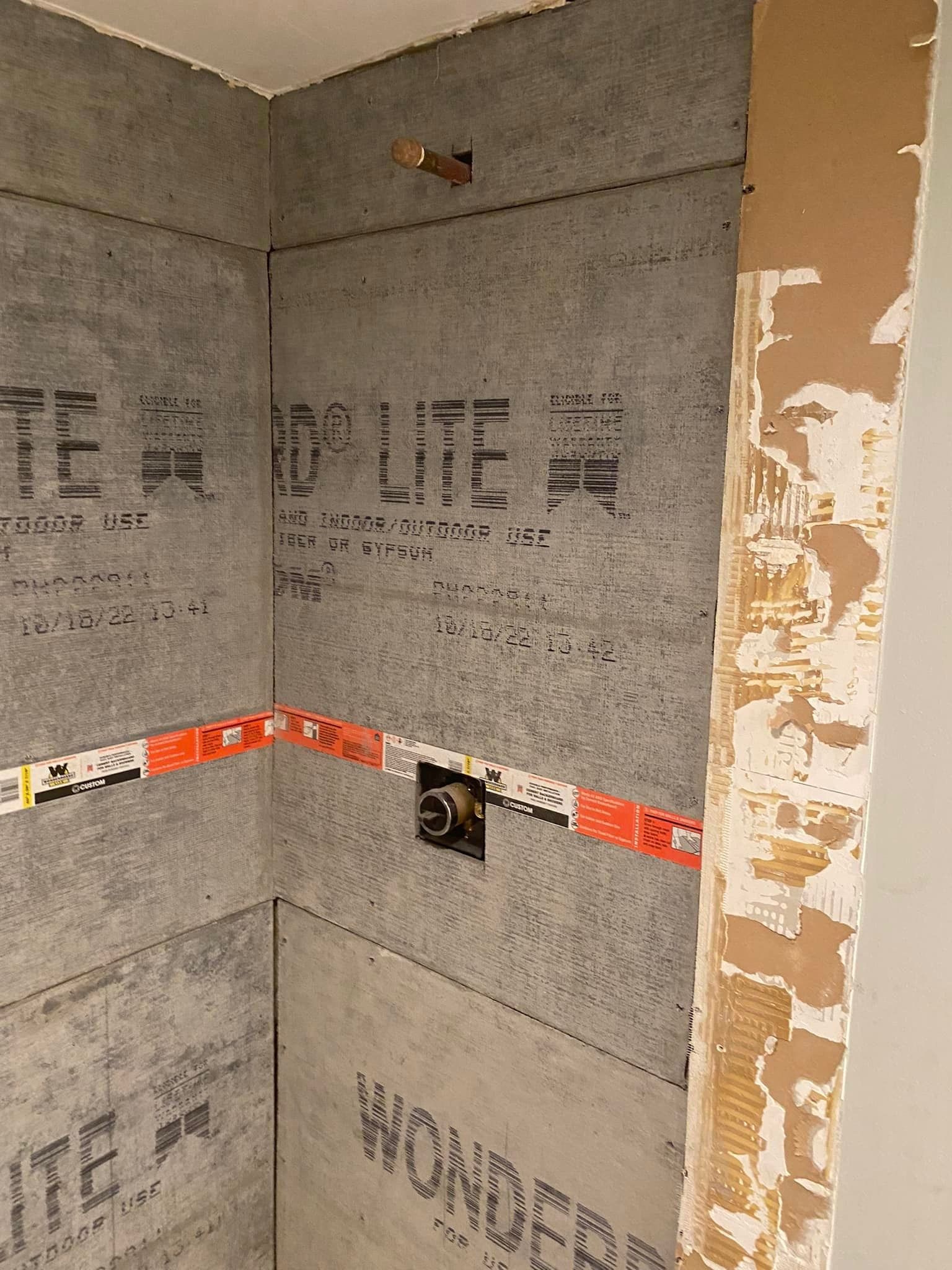 A corner of a bathroom with a gray wall and the words `` wonder '' written on it.