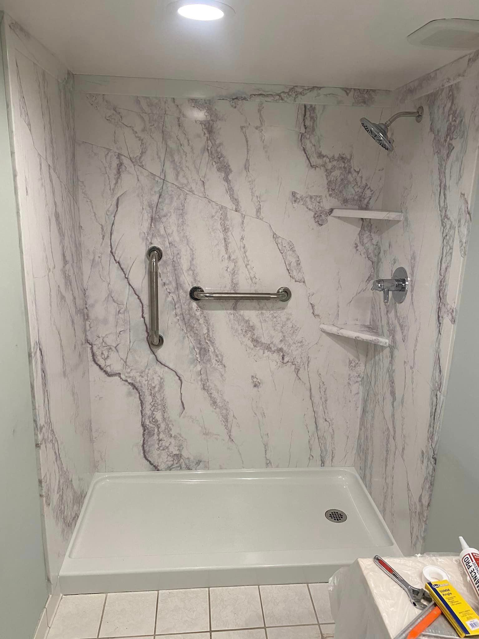 A bathroom with a shower stall and a hand rail.