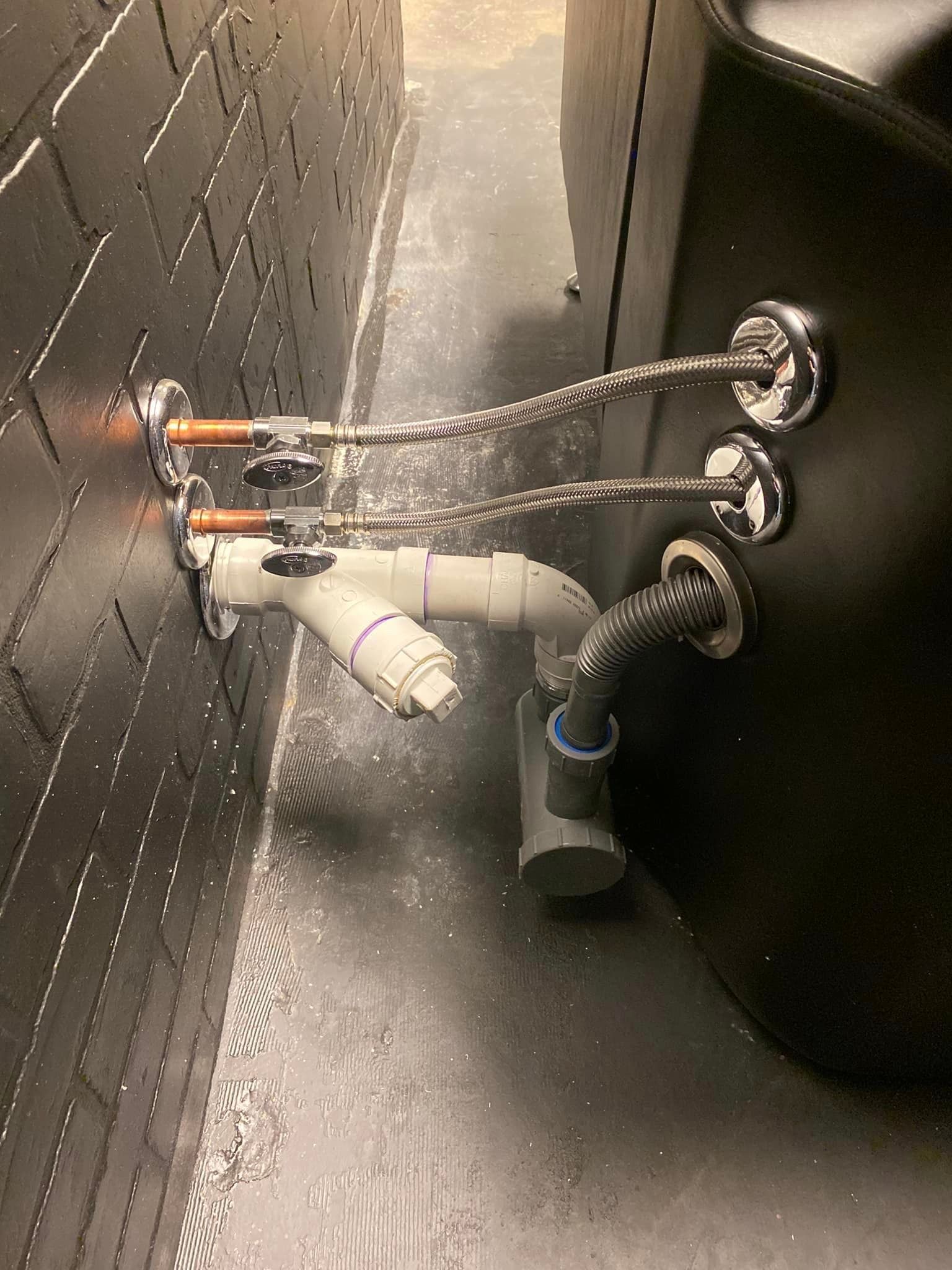 A close up of a pipe with water coming out of it in a bathroom.