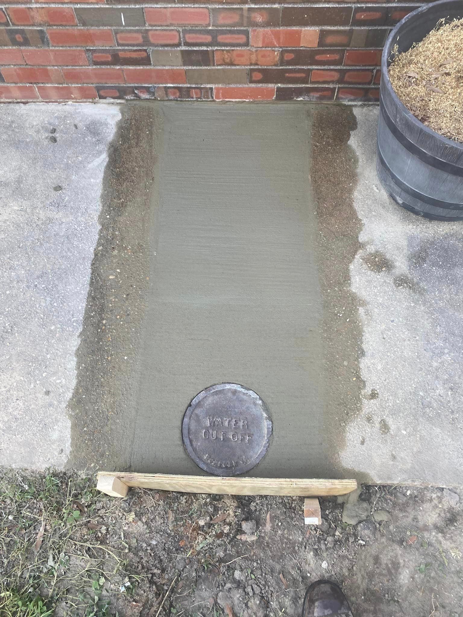 A concrete walkway is being built in front of a brick building.