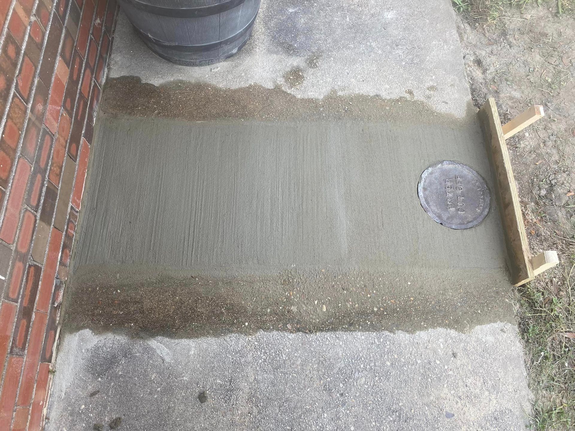 A concrete walkway is being built next to a brick wall.