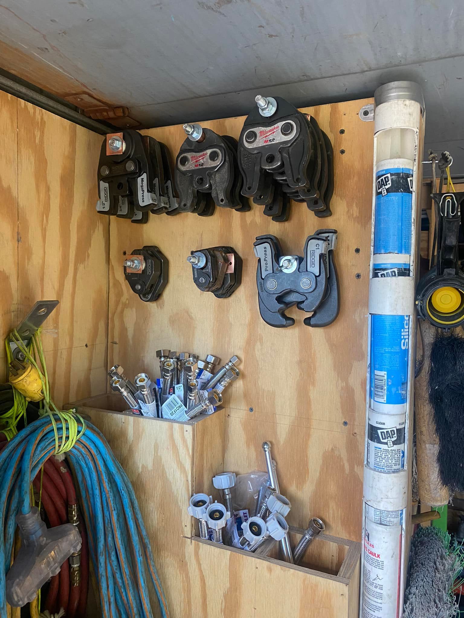 A wooden wall with a bunch of tools hanging on it.
