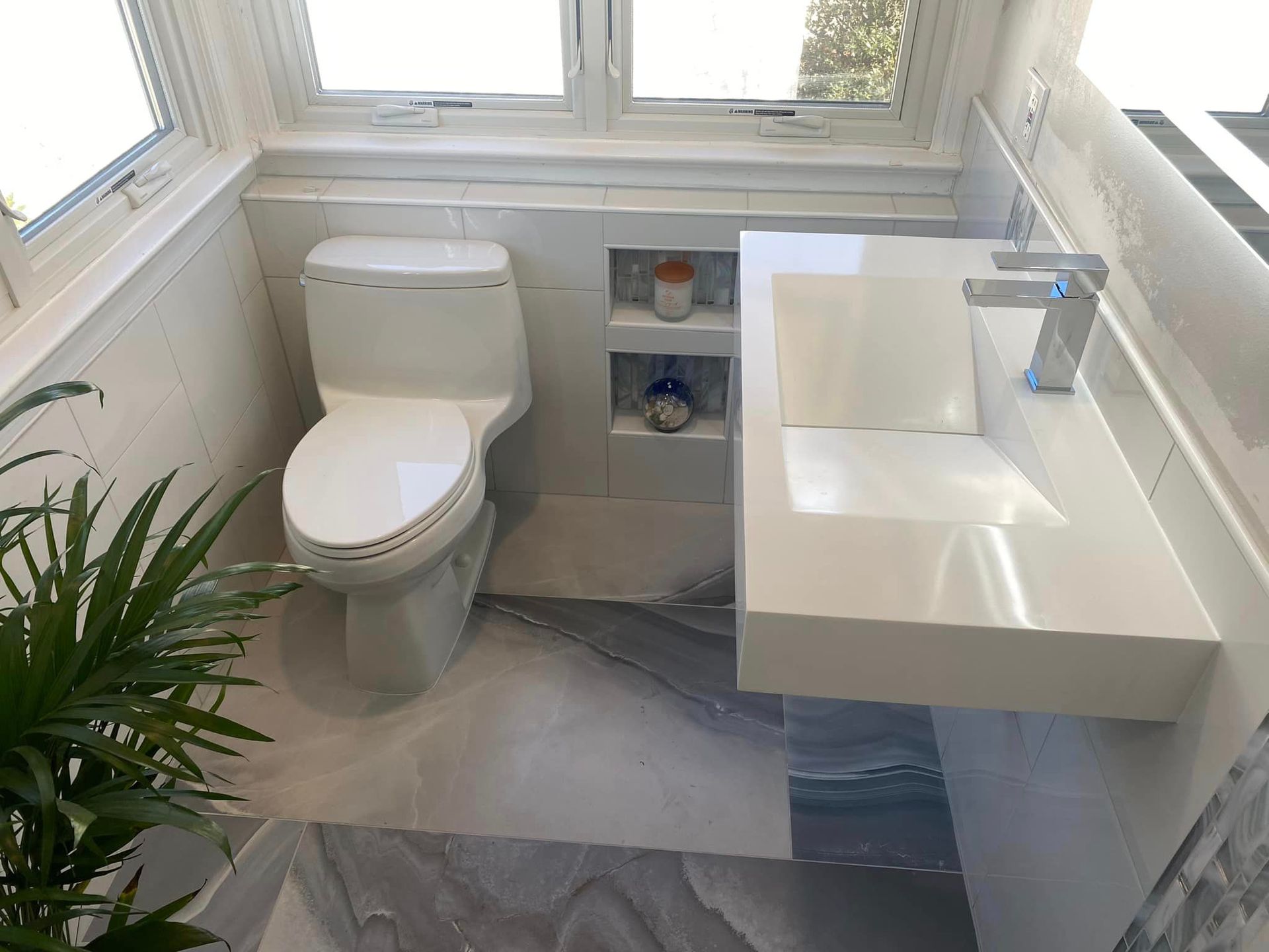 A bathroom with a toilet , sink and window.