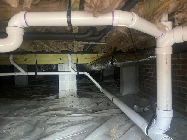 A bunch of white pipes are connected to each other in a basement.