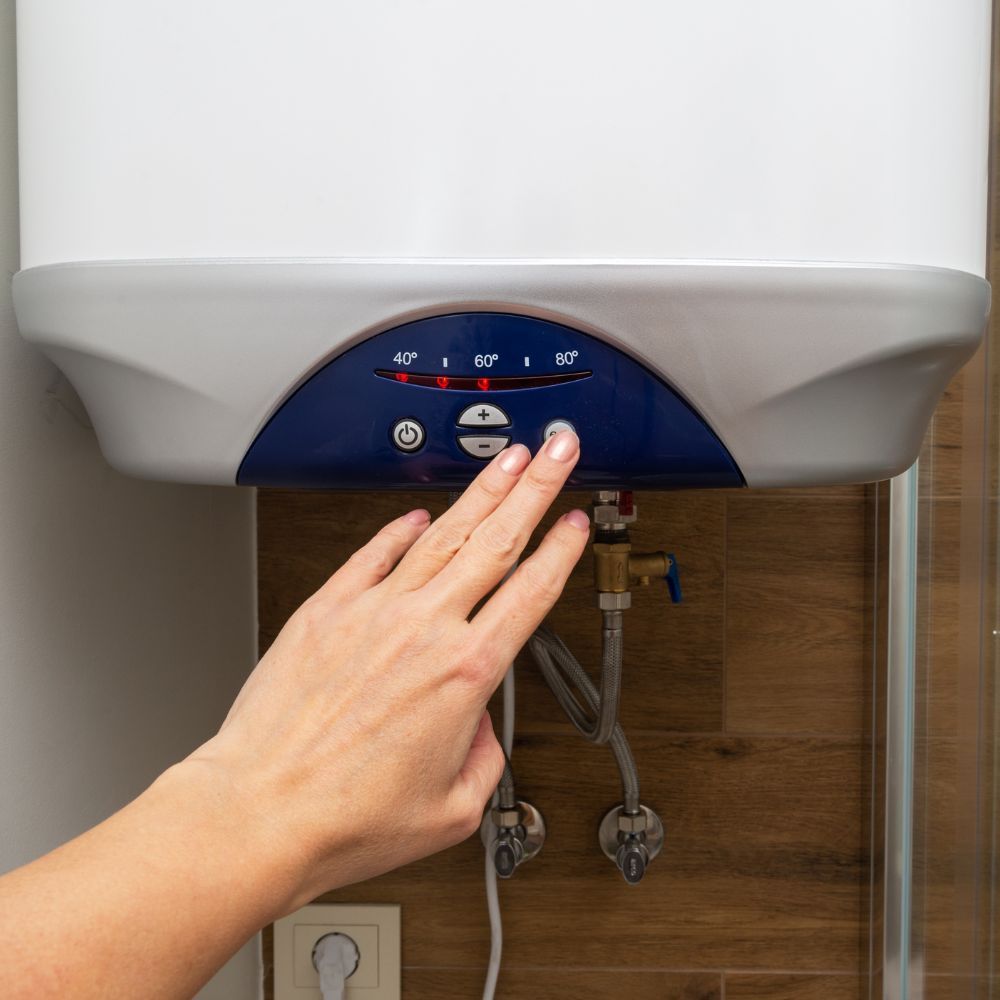 A person is pressing a button on a water heater.