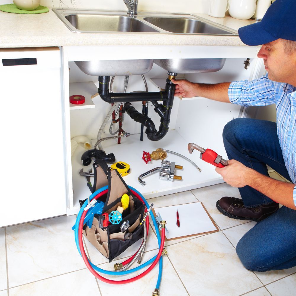 A plumber is fixing a sink in a kitchen