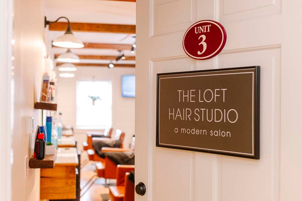 A sign on a door that says the loft hair studio