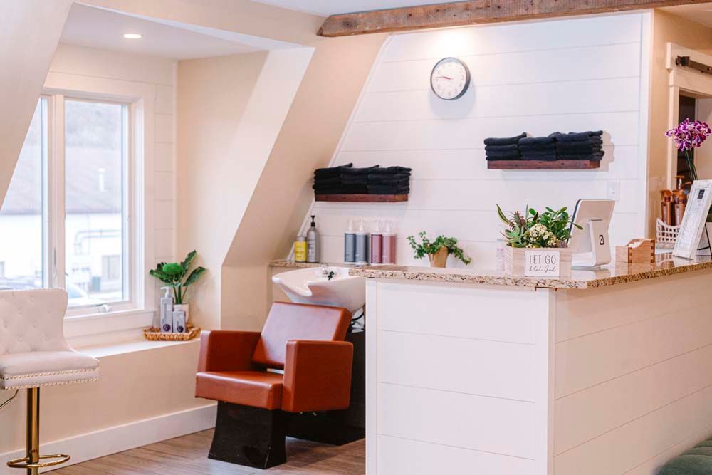 A salon with a chair , sink , counter and window.