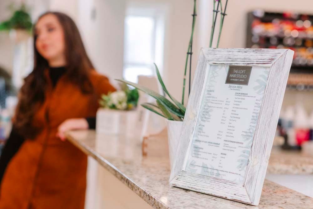 A woman is standing behind a counter with a framed picture on it.