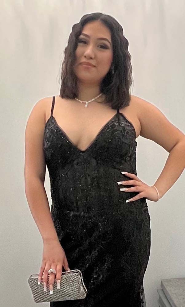 A woman in a black dress is holding a silver clutch.