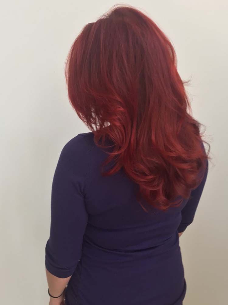 A woman with long red hair is wearing a blue shirt