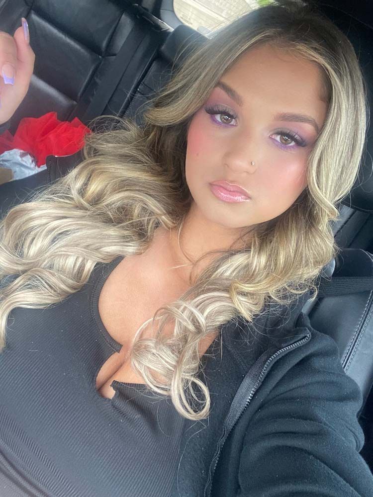 A woman is taking a selfie in the back seat of a car.