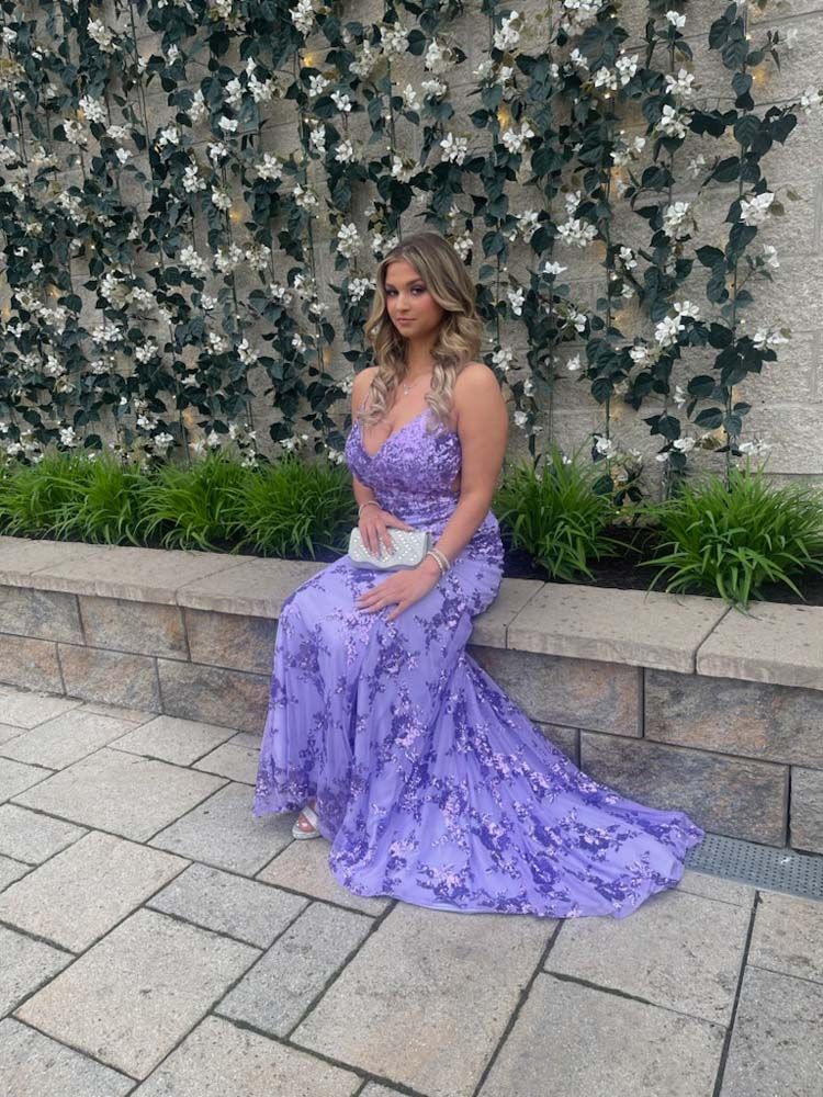 A woman in a purple dress is sitting on a bench.