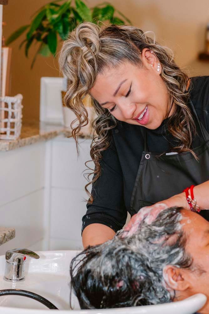 A woman is washing another woman 's hair in a sink.