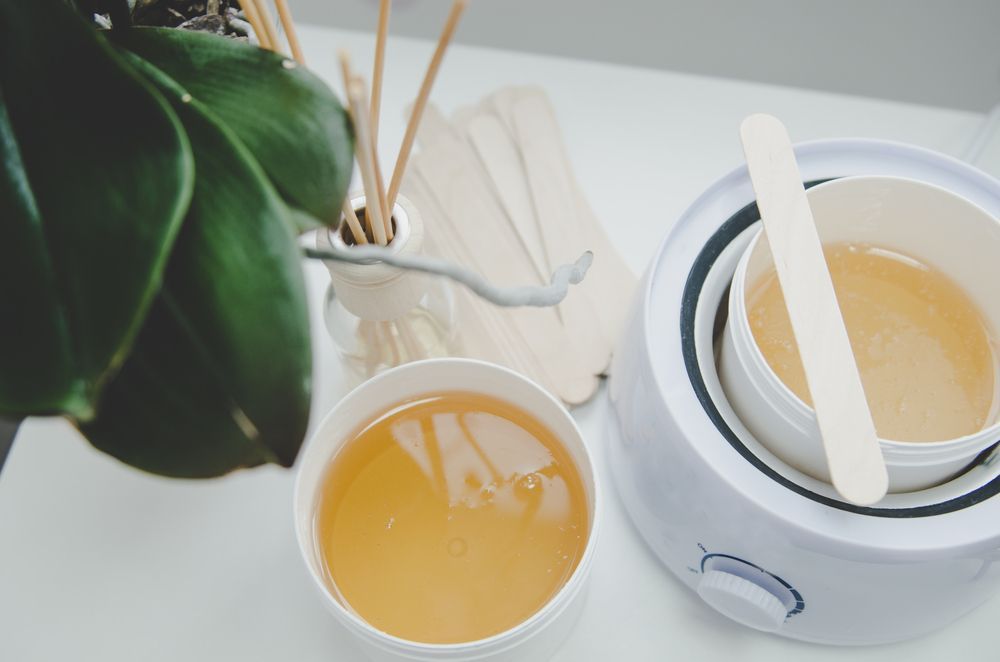 There are two bowls of wax next to a wax warmer.