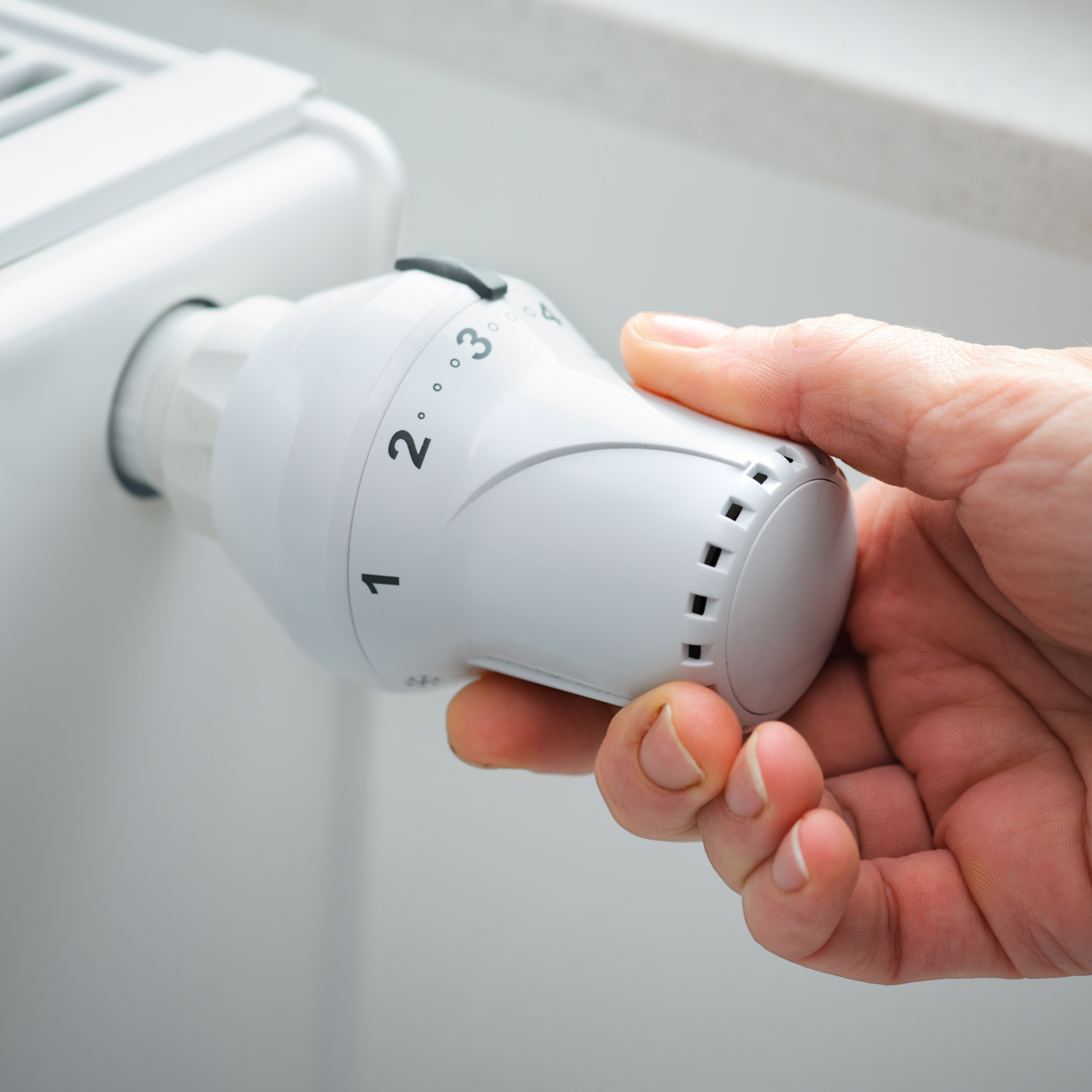 a person is adjusting a thermostat on a radiator .