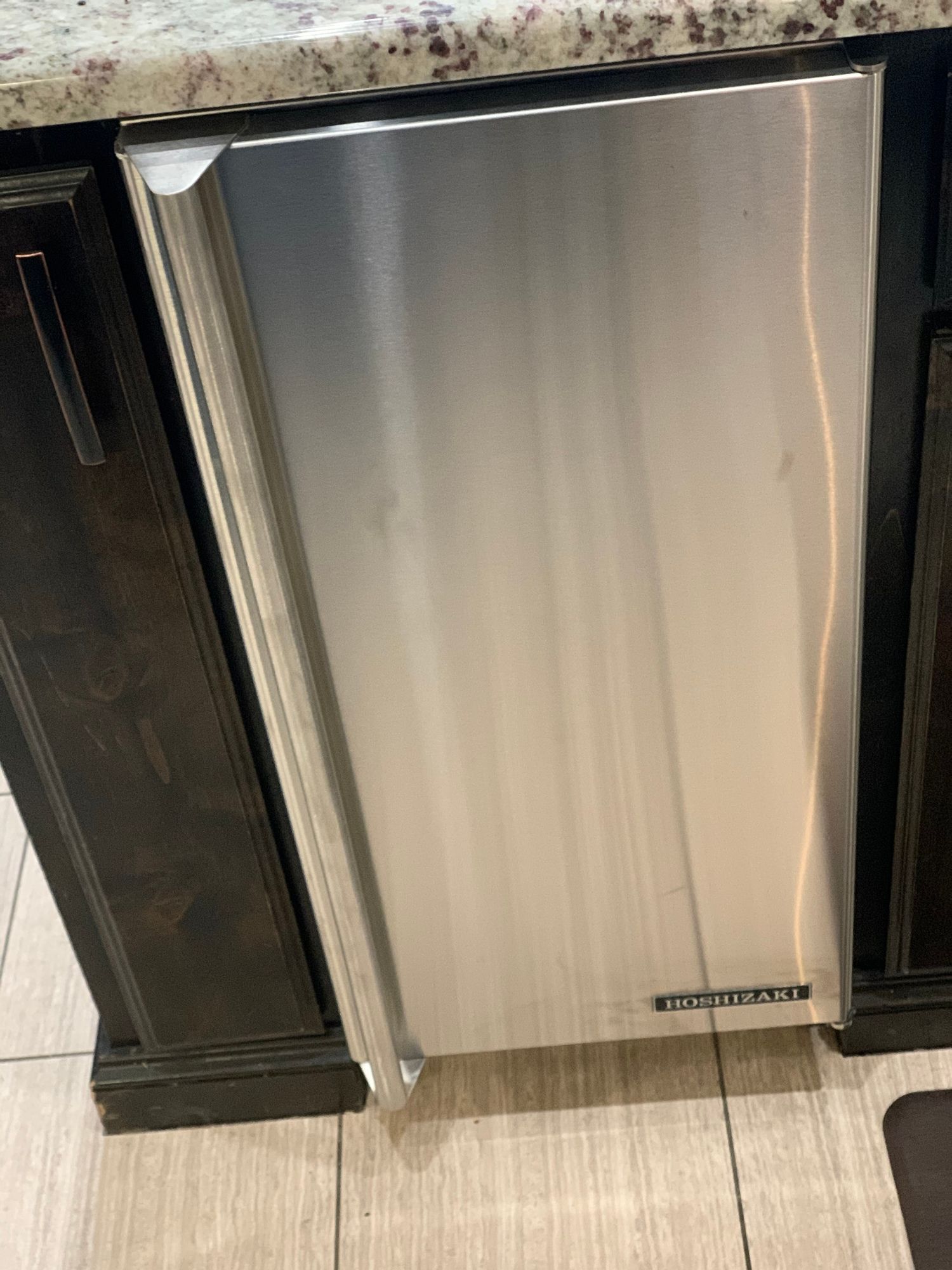 a stainless steel refrigerator is sitting under a counter in a kitchen .