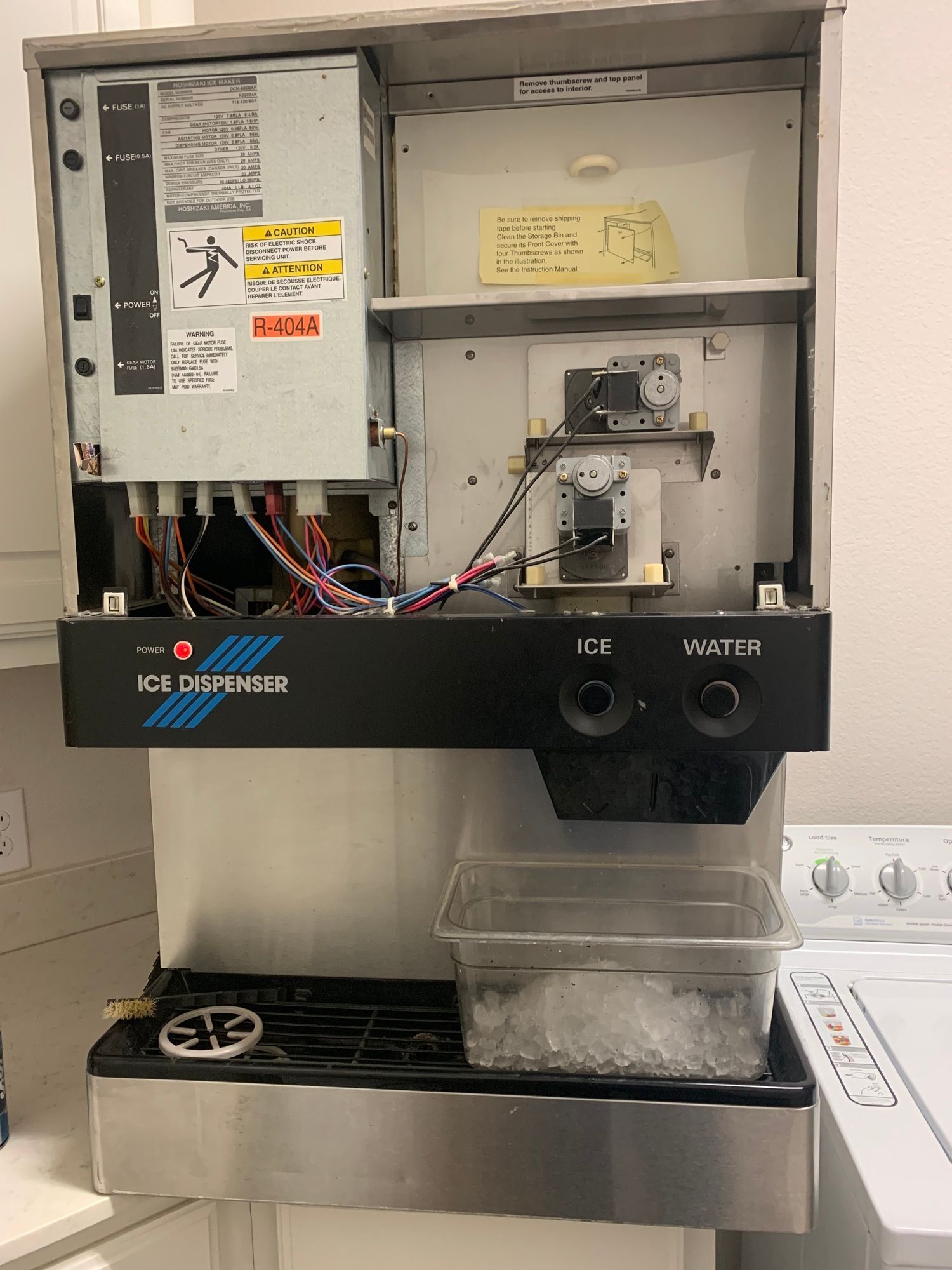 a stainless steel ice maker is sitting in a kitchen next to a washer and dryer .