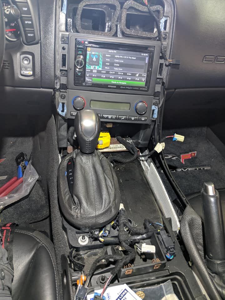 The dashboard of a car is being removed and a radio is being installed