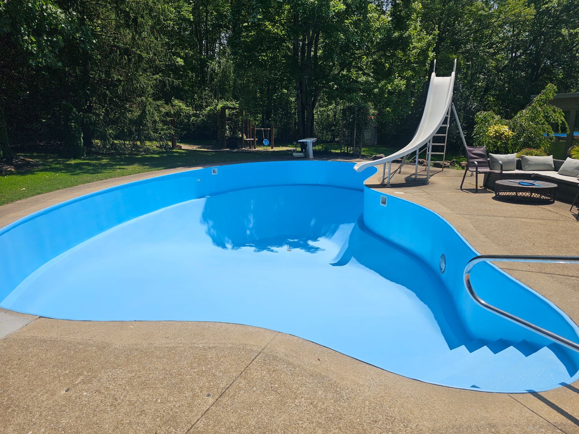 Swimming pool after professional painting by NORTHCOAST Painting and Pressure Washing — freshly painted blue pool in Northeast Ohio