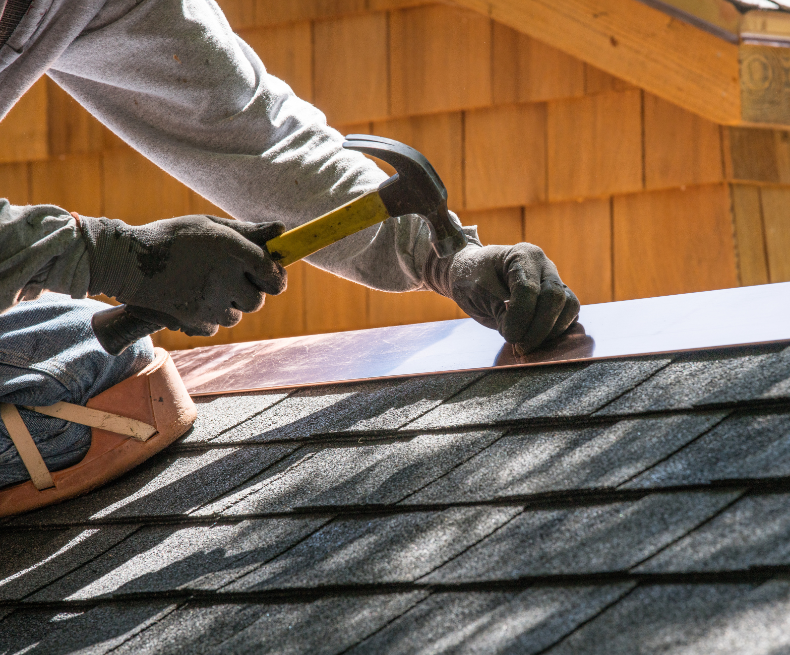 A man is working on a roof with a hammer