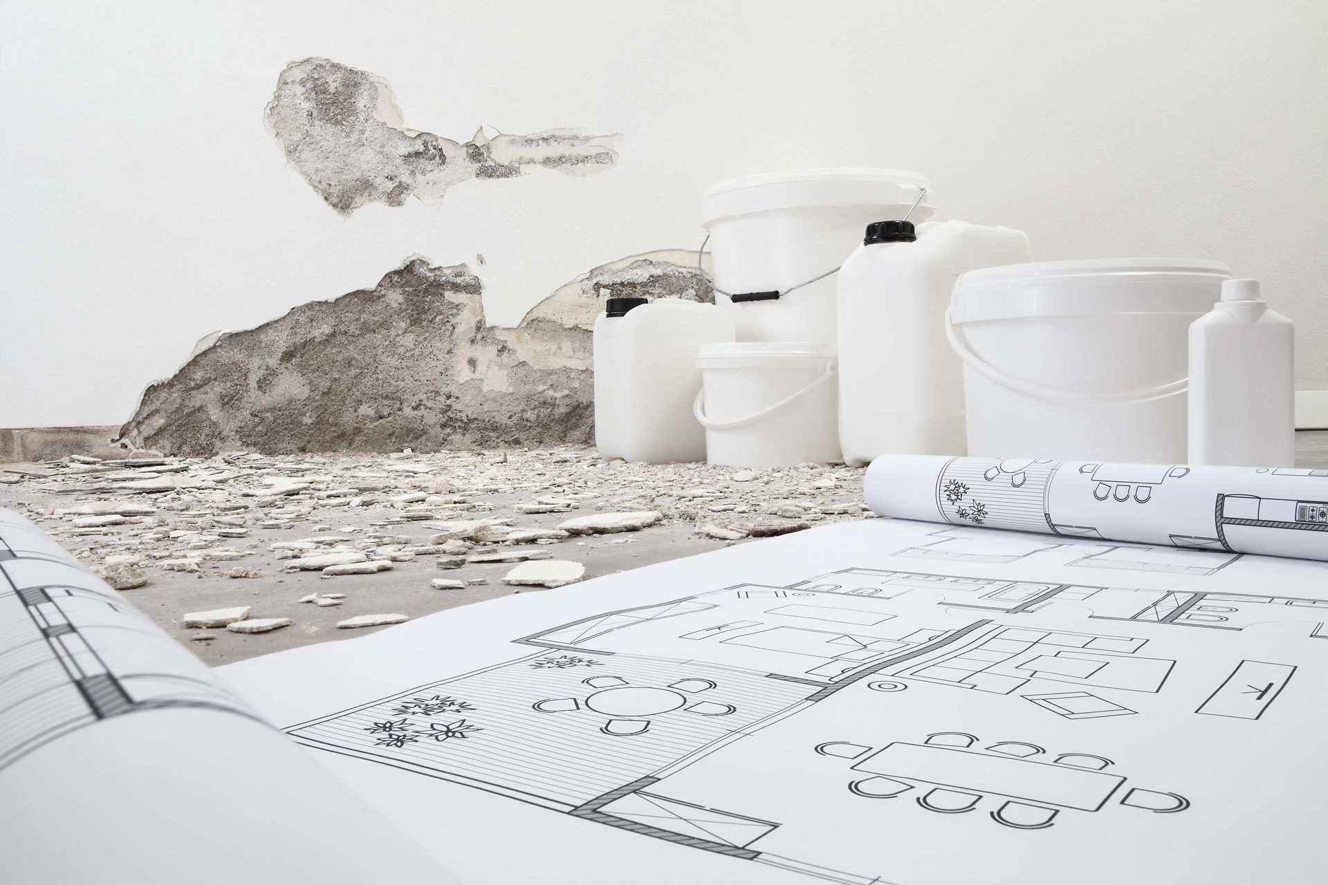 Un mucchio di secchi bianchi e bottiglie sono appoggiati sul pavimento.