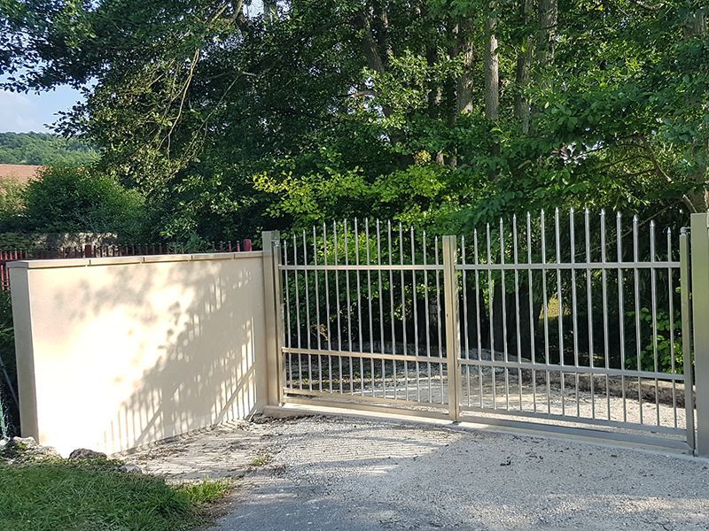 Una recinzione metallica circonda un vialetto con alberi sullo sfondo.