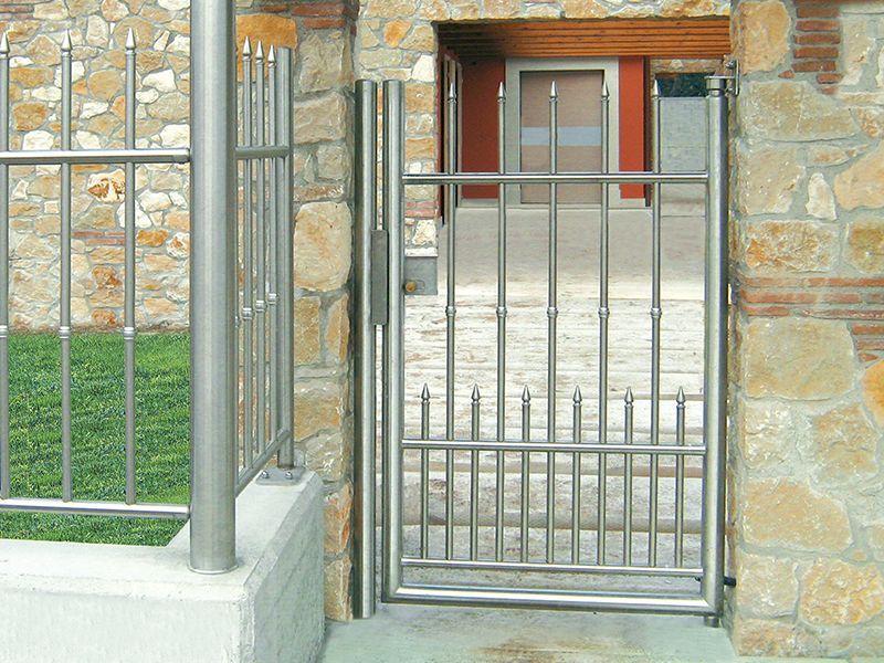 Un cancello in acciaio inossidabile davanti a un muro di pietra