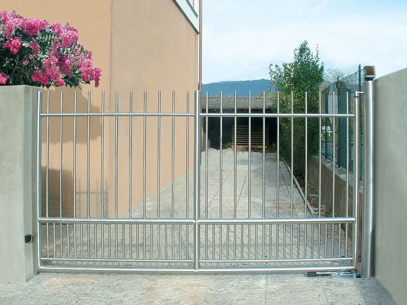 Un cancello in acciaio inox è aperto su un vialetto