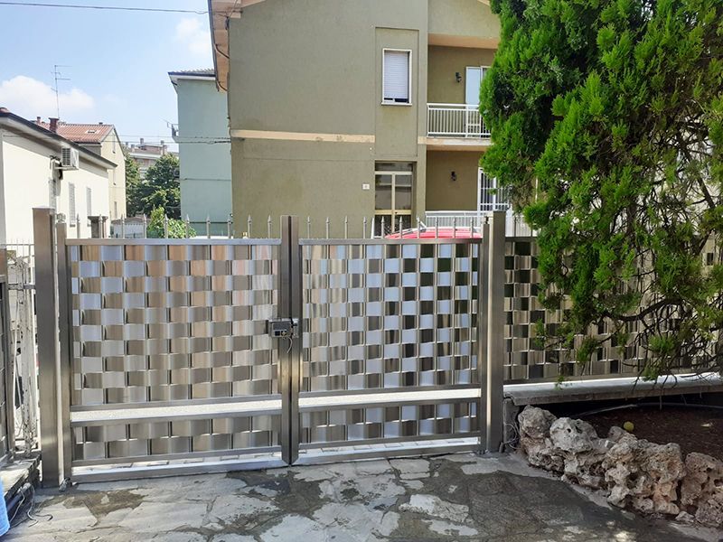 Davanti ad un edificio si trova un cancello in acciaio inox con motivo a scacchiera