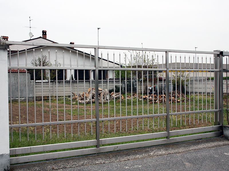 Una recinzione metallica con una casa sullo sfondo