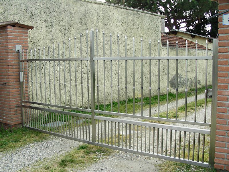 Davanti ad un muro di mattoni è aperto un cancello in acciaio inox