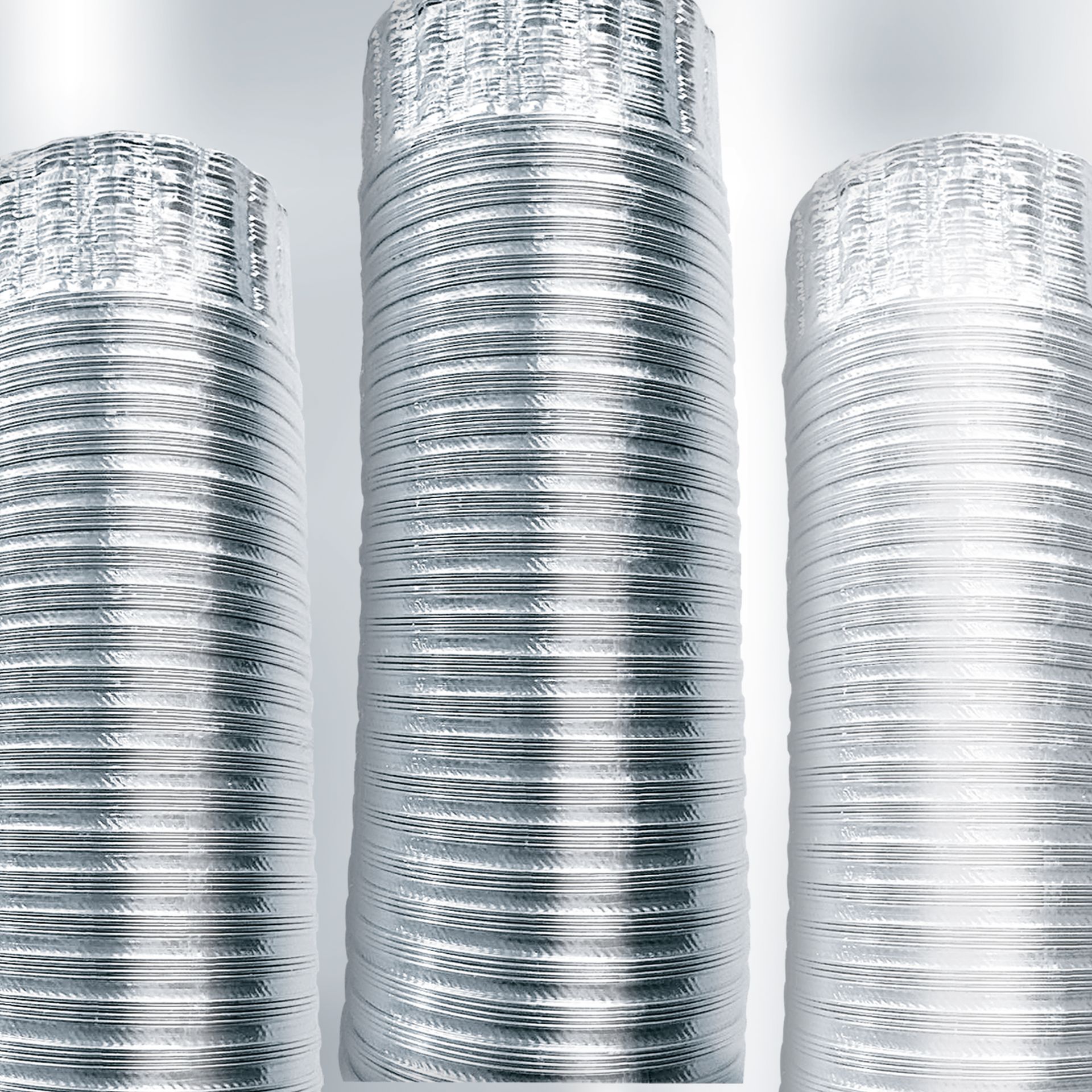 Tre condotti di alluminio sono impilati uno sopra l'altro su una superficie bianca.