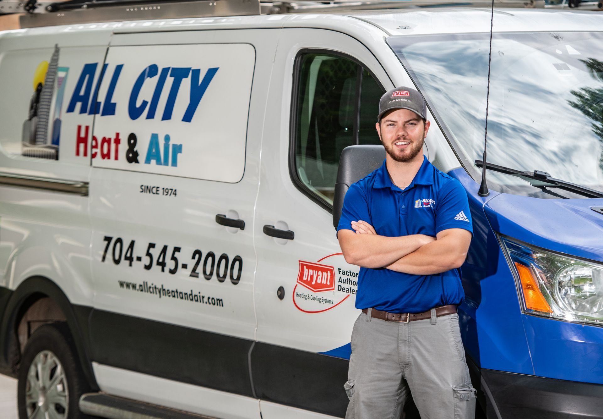 An All City Heat and Air technician is standing in front of an All City Heat and Air van.